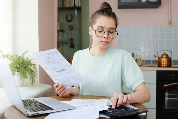 istock Yong woman budgeting, managing utilities expences, writing financial plan, analyzing her spendings 1001479894