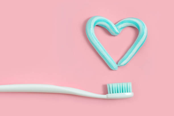 brosses à dents et dentifrice de couleur turquoise en forme de coeur sur fond rose. concept de soins dentaire et soins de santé. - toothpaste photos et images de collection