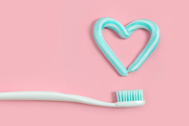 escovas de dentes e pasta dentífrica cor turquesa em forma de coração no fundo rosa. conceito de saúde e odontológico. - toothbrush pink turquoise blue - fotografias e filmes do acervo
