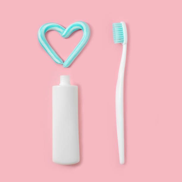 escovas de dentes e pasta dentífrica cor turquesa em forma de coração no fundo rosa. conceito de saúde e odontológico. - toothbrush pink turquoise blue - fotografias e filmes do acervo