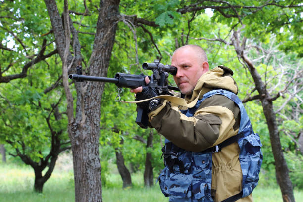 istock Man hunter with arms in the forest. Sighting the gun barrel at the target. 1001486346