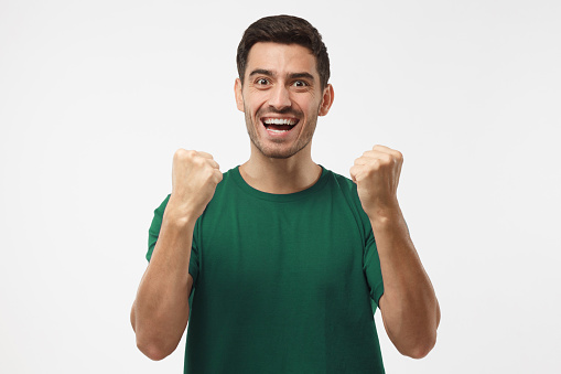 Soccer fan in green t-shirt celebrating win of his team, screaming,  isolated on gray background