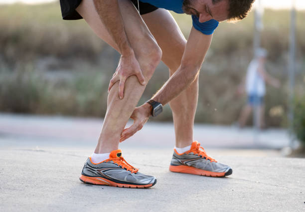 primo classificato toccando doloroso tortino o rotto caviglia shin o polpaccio atleta runner allenamento incidente sport corsa caviglia distorsione concetto - stinco gamba umana foto e immagini stock