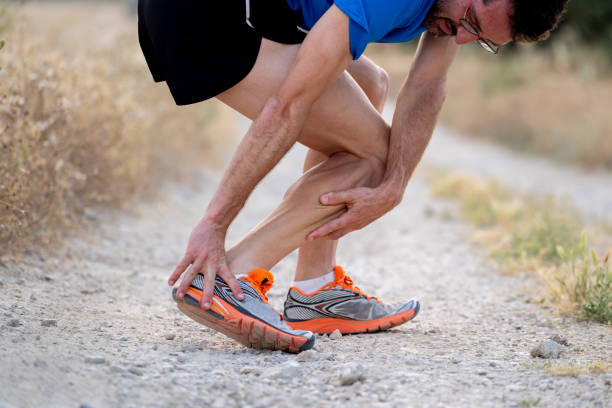 close up of runner touching painful twisted or broken ankle shin or calf athlete runner training accident sport running ankle sprain concept - twisted ankle fotos imagens e fotografias de stock