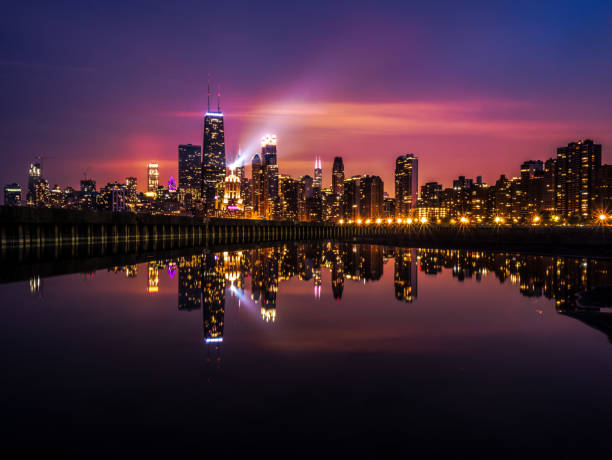 建物のライトとスポット ライトが空に輝いてを水の穏やかなプールに反映して空にピンクは紫、青雲が夕日に美しい長時間露光夜のシカゴのスカイラインの写真します。 - chicago at night ストックフォトと画像