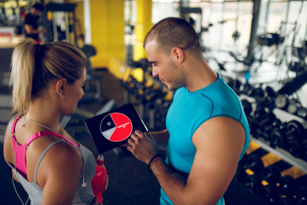 istock Young woman discussing workout progress with fitness instructor 1001506144