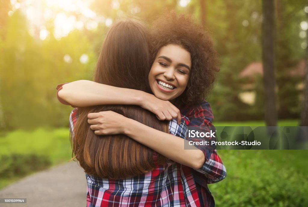 Two happy young girls hug each other outdoors Bff long-awaited meeting. Happy girls hug in park after long separation, copy space Friendship Stock Photo