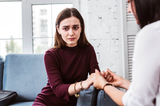 istock Young woman holding hands with her psychologist and feeling scared 1001510406