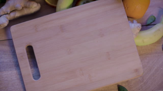 Placing Cutting board on a Table, with Banana, Almonds, Spinach and Oranges