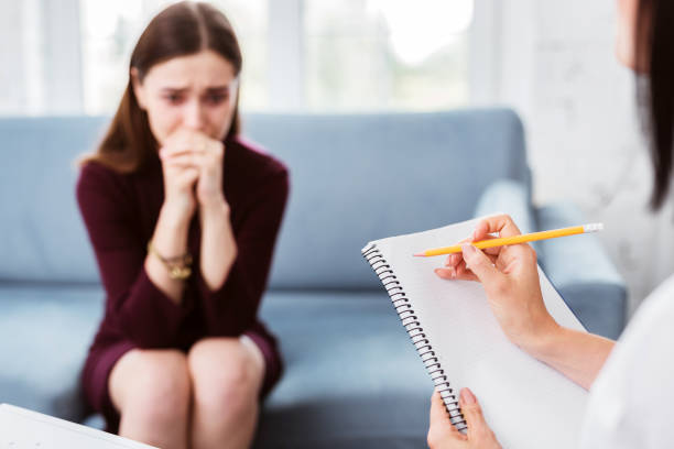 istock Worried woman sitting on a sofa and a psychologist making notes 1001516354