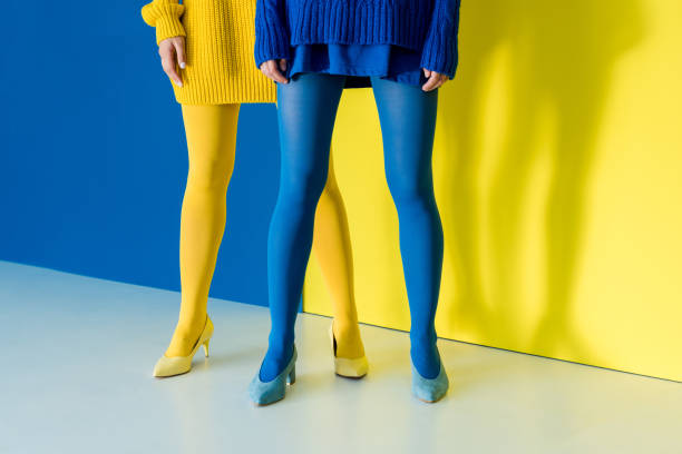 vista ritagliata delle donne che indossano collant blu e giallo su sfondo blu e giallo - collant foto e immagini stock