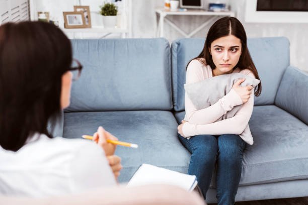 istock Young woman hugging a cushion and looking scared 1001532950