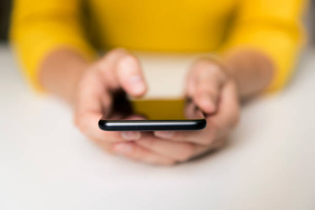istock Hand of woman using smartphone on white table. Communication and technology concept 1001533408