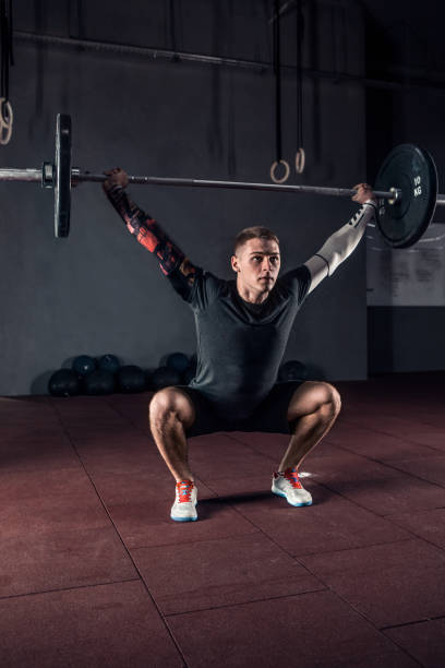 Young athlete lifting the barbell in gym. Gym training