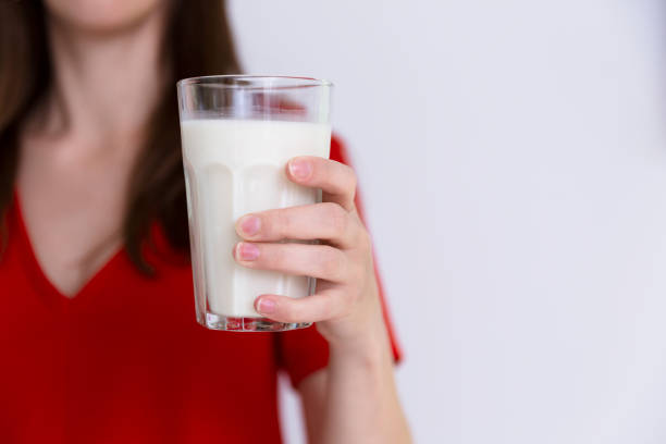 Woman in red dress holding glass of milk. Lactose intolerance, cow milk, health concept stock photo