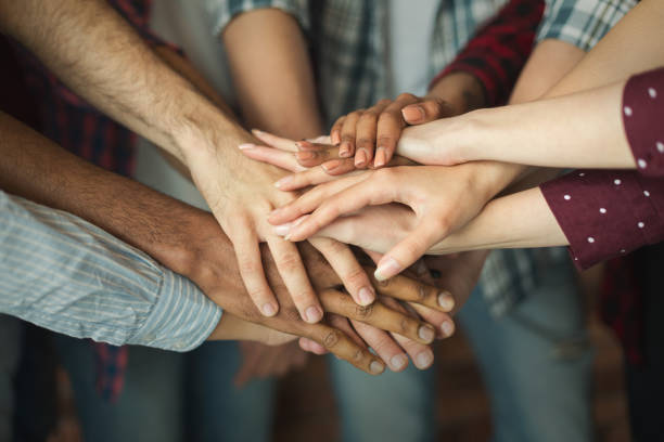 Group of friends holding hands together Friendship and teamwork. Multiethnic company of friends stacked hands together, copy space harmony stock pictures, royalty-free photos & images