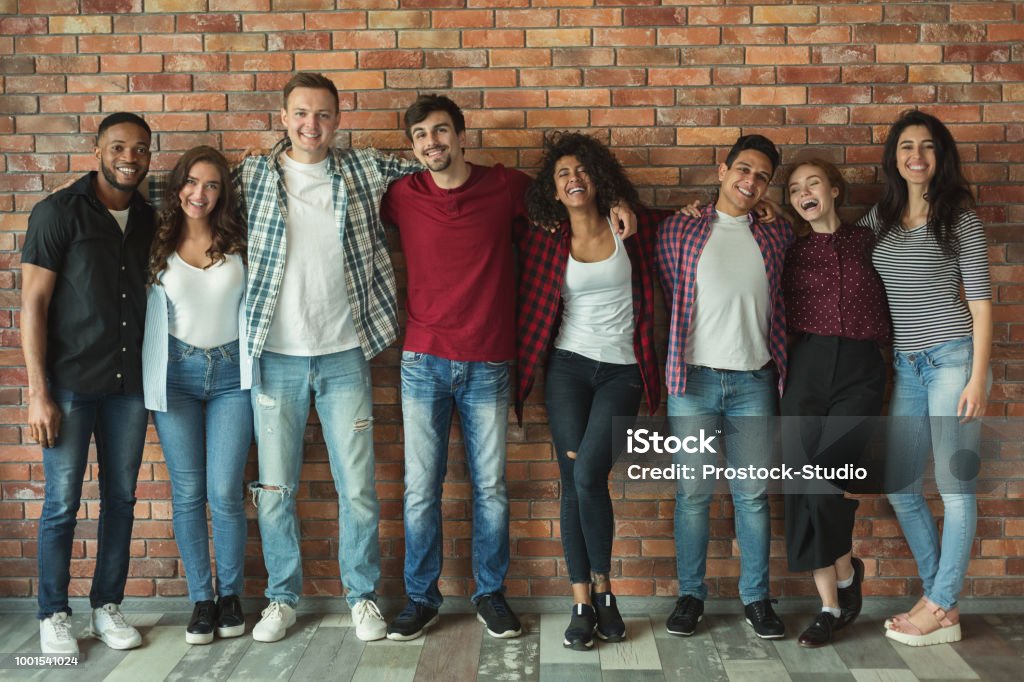 Happy diverse people bonding together International friendship and tolerance. Cheerful multiethnic friends laughing and embracing, posing for group portrait, copy space Multiracial Group Stock Photo