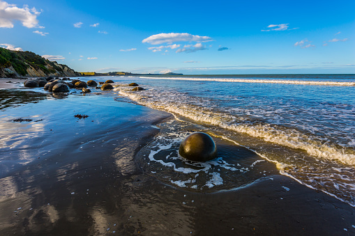 The concept of active, eco and photo tourism. Boulders Moeraki - a group of large spherical boulders on the beach Koekokhe. Ocean evening tide. Travel to New Zealand