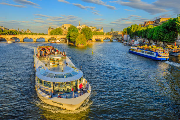 Paris, France - July 1, 2017: Tourist cruise on Seine river. Bateau mouche from Pont Neuf bridge and Notre Dame church on background. Aerial view of touristic cruise from the Pont des Arts at sunset.