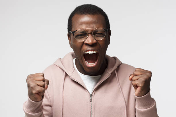 istock Shut up concept. Mad young african american man shouting, gesturing with hands. Studio portrait of angry and irritated black male yelling, looking crazy and full of anger 1001563448
