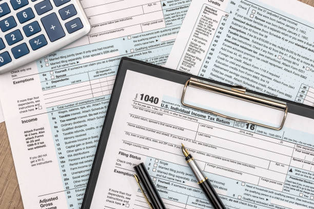1040稅形式在木桌用筆和計算機 - 1040 稅表 圖片 個照片及圖片檔