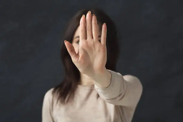 Young woman saying no. Girl denying proposal, making stop gesture with her hand. Studio shot, copy space