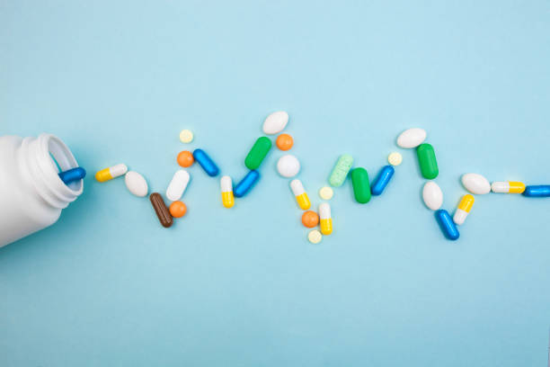istock Multi-colored tablets and capsules in pulsation heartbeat white bottle for tablets, pharmaceutical medicine pills on blue background, an analgesic against diseases 1001571356