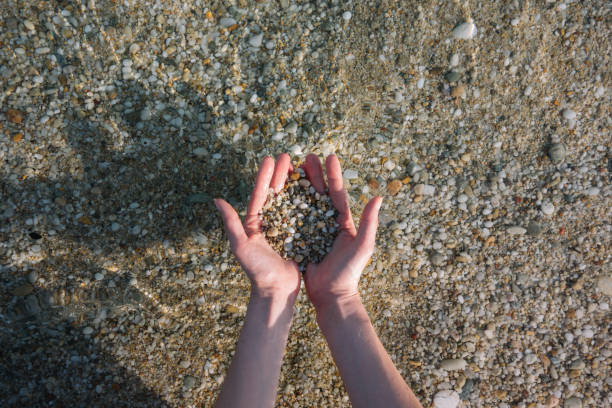 istock Girl on a beach holding sand in her palms 1001575894
