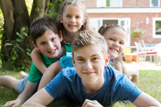 Photo of Portrait Of Four Brothers And Sisters Lying In Garden At Home