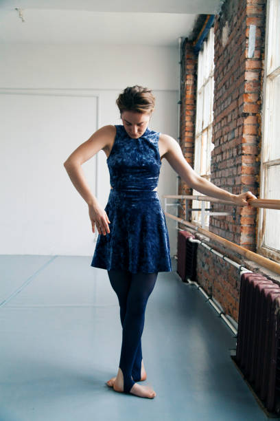 istock Young female performer practicing ballet excersices near ballet barre in white spacious loft. Natural lighting. Vertical composition, copy space. 1001580082