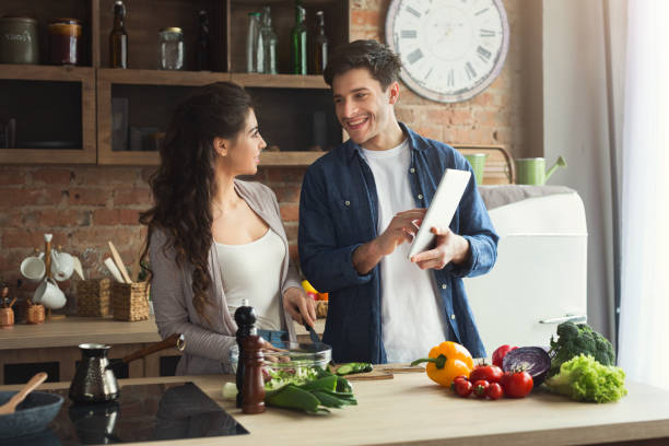istock Beautiful young couple reading recipe on tablet 1001580104