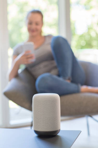 istock Woman Streams Music From Mobile Phone To Wireless Speaker 1001580752