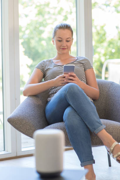 istock Woman Streams Music From Mobile Phone To Wireless Speaker 1001580816