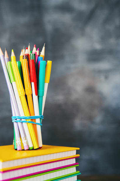 istock Colorful pencils and pens against weathered chalkboard 1001584308