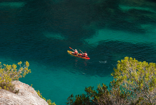 Two adults paddling with baby on board in the colorful Hawaiian sea of Menorca