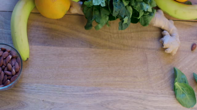 Placing Cutting board on a Table, with Banana, Almonds, Spinach and Oranges