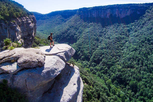 Risky mountaineer on a cliff looking at the horizon. Aerial view