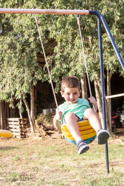 cute little blond boy swinging on swings - freedom tire swing tire swing imagens e fotografias de stock