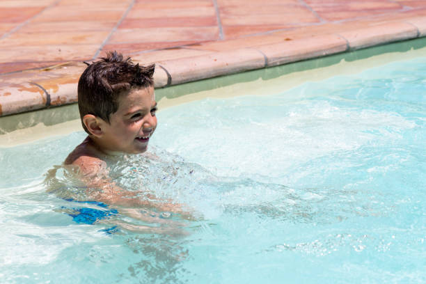 istock Cute little boy playing in the swimming pool at summer 1001608696