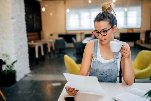 istock Pensive young entrepreneur examining papers while sitting at table in coffee shop. 1001611622