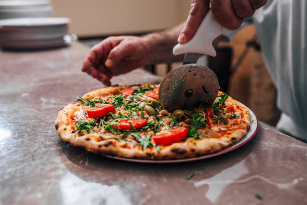 istock Close-up image of hand of chef baker cutting pizza. 1001611848