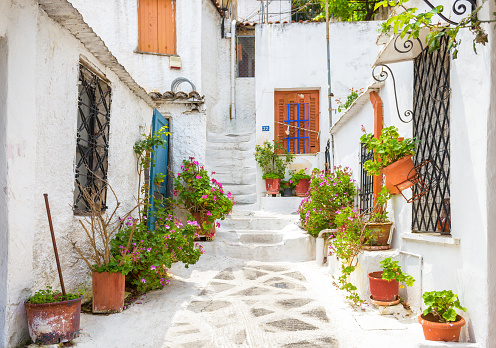 Scenic narrow street with old houses in Anafiotika in Plaka district, Athens, Greece. Plaka is one of the main tourist attractions of Athens. Beautiful traditional alley at Acropolis slope in Athens.