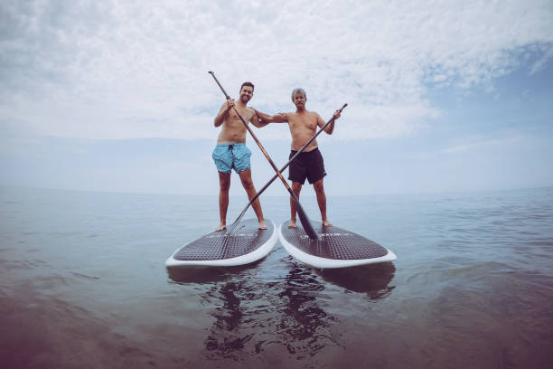 With father on surfing Father and son sail on a SUP board on the sea. paddleboard surfing water sport low angle view stock pictures, royalty-free photos & images
