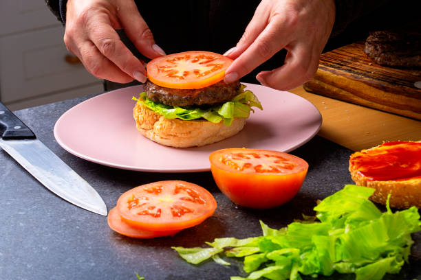 istock Tomato is place on top of hamburger patty 1001618224