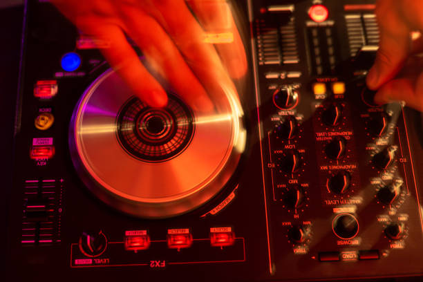 Dj mixing on turntables with color light effects. Soft focus on hand. Close-up. Fun, youth, entertainment and fest concept