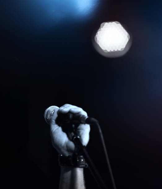 istock Hand holds microphone on the stage, close-up 1001631352