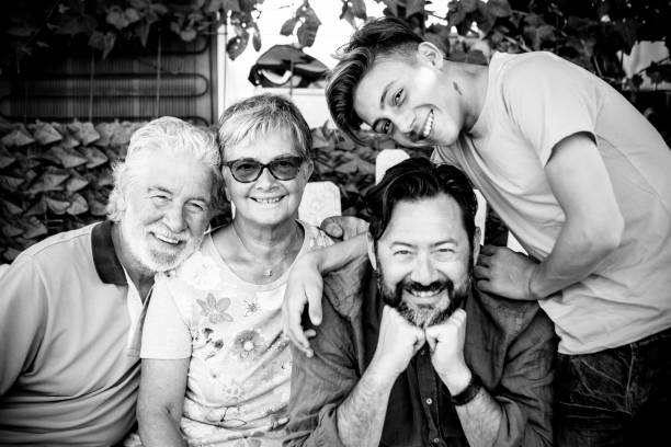 four different mixed generations grandfather father son all together in leisure activity. mobile phones on the table to represent technology and family concept connected to the modern world. colored clothes and happiness scene