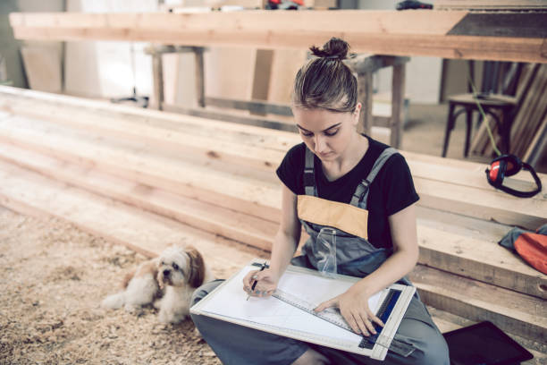 istock Female Carpenter Designing And Drawing New Project Ideas With Pet Puppy 1001649964