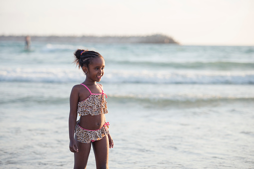 Portrait of 6 years old girl in swimming wear on the beach at sunset time.