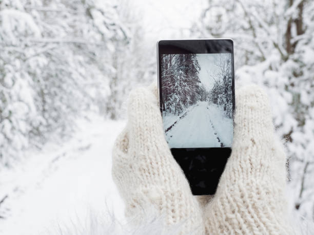 ragazza tiene in mano un cellulare in guanti di lana - glove winter wool touching foto e immagini stock